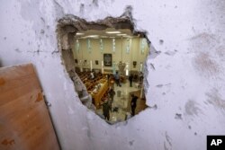 Israeli security forces inspect a damaged synagogue after it was hit by a rocket fired from the Gaza Strip, in Ashkelon, May 16, 2021.