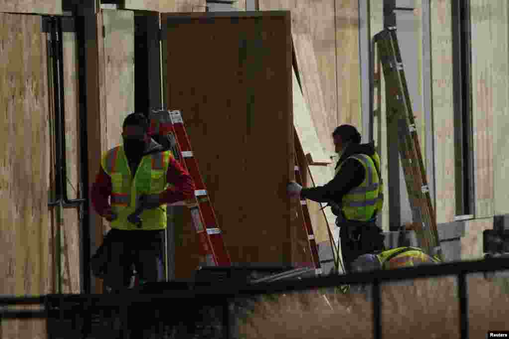 Operarios instalan paneles de madera sobre los escaparates de numerosos negocios. 16 de enero de 2021.