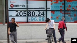 People stand by an electronic stock board of a securities firm in Tokyo, Wednesday, Aug. 21, 2019. Asia stock markets followed Wall Street lower Wednesday as investors looked ahead to a speech by the Federal Reserve chairman for signs of possible…