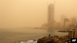 A man walks on the rocky coastal area along the Beirut coastline during a sandstorm in Beirut, Lebanon, Sept. 8, 2015. 