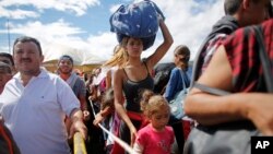 A woman carrying a bundle on her head wait in line to cross the border into Colombia through the Simon Bolivar bridge in San Antonio del Tachira, Venezuela, July 17, 2016.