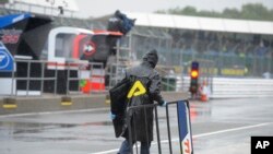 A member of the team of Moto3 rider Vicente Perez of Spain carries some gear on the pit lane as the track remains closed for the British Motorcycle Grand Prix at the Silverstone racetrack in Silverstone, England, Sunday, Aug. 26, 2018. The start of the ra