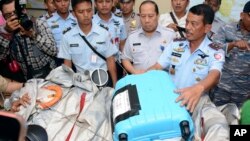 Indonesian Air Force Rear Marshall Dwi Putranto, right, shows airplane parts and a suitcase found floating on the water near the site where AirAsia Flight 8501 disappeared, at the airbase in Pangkalan Bun, Central Borneo, Indonesia, Dec. 30, 2014. 