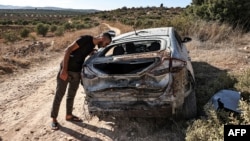 A man inspects a destroyed vehicle after an Israeli army raid along a road between Jenin and Tubas in the north of the occupied West Bank on Aug. 28, 2024.