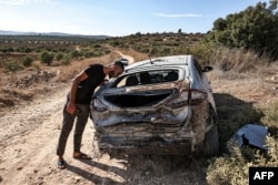 A man inspects a destroyed vehicle after an Israeli army raid along a road between Jenin and Tubas in the north of the occupied West Bank on Aug. 28, 2024.