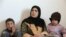 A Syrian woman at home with two of her children inside their apartment in the city of Mafraq, in Northern Jordan. Her husband has remained in Syria.