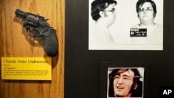 FILE - The gun used by Mark David Chapman to kill John Lennon is displayed next to their pictures at a small museum in the Forensic Investigation Division of the New York Police Department in New York, Dec. 8, 2015. 