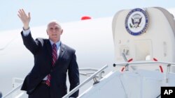 Vice President Mike Pence waves as he stops off Air Force Two after arriving at the Des Moines International Airport before meeting with faith leaders and food industry executives in response to the coronavirus pandemic, May 8, 2020, in Des Moines, Iowa. 