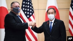 Japan's Prime Minister Yoshihide Suga, right, and U.S. Secretary of State Mike Pompeo, left, greet prior to their meeting at the prime minister's office in Tokyo, Tuesday, Oct. 6, 2020. (Charly Triballeau/Pool Photo via AP)