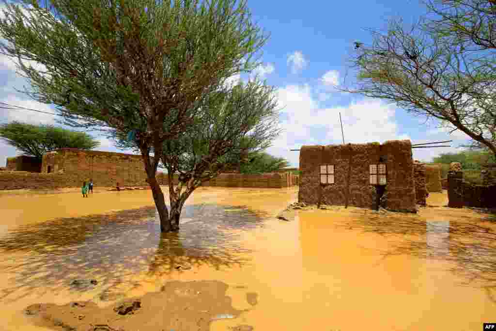 Sudanese children stand on the other side of a flooded street, after torrential rain lead to landslides and flash floods, in the town of Umm Dawan Ban, southeast of the capital Khartoum.