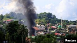 Smoke billowing from a burning building is seen as government troops continue their assault on insurgents from the Maute group, who have taken over large parts of Marawi City, Philippines, June 1, 2017. 