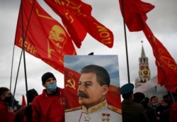 FILE - A supporter of the Russian Communist Party holds a portrait of Soviet leader Josef Stalin during a procession marking the anniversary of the 1917 Bolshevik Revolution, in Red Square in Moscow, Russia, Nov. 7, 2020.