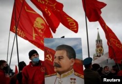 FILE - A supporter of the Russian Communist Party holds a portrait of Soviet leader Josef Stalin during a procession marking the anniversary of the 1917 Bolshevik Revolution, in Red Square in Moscow, Russia, Nov. 7, 2020.