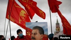 FILE - A supporter of the Russian Communist Party holds a portrait of Soviet leader Josef Stalin during a procession marking the anniversary of the 1917 Bolshevik Revolution, in Red Square in Moscow, Russia, Nov. 7, 2020. 