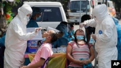 Petugas kesehatan melakukan tes swab COVID-19 pada warga saat memantau kasus di sebuah desa di Kota Quezon, Filipina, Senin, 31 Mei 2021. (Foto: AP)