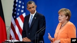 U.S. President Barack Obama listens as German Chancellor Angela Merkel addresses the media during a press conference at the chancellery in Berlin, June 19, 2013.