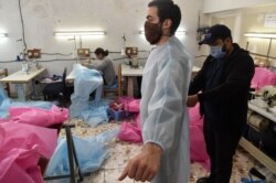 FILE - Algerian volunteers prepare personal protection equipment, consisting of face masks and body suits to help combat the coronavirus epidemic, in the capital Algiers on April 8, 2020.