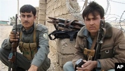 Afghan policemen guard main gate of joint civilian-military base where two British soldiers, part of the NATO forces, were killed, Lashkar Gah, Helmand province, Afghanistan, March 26, 2012.