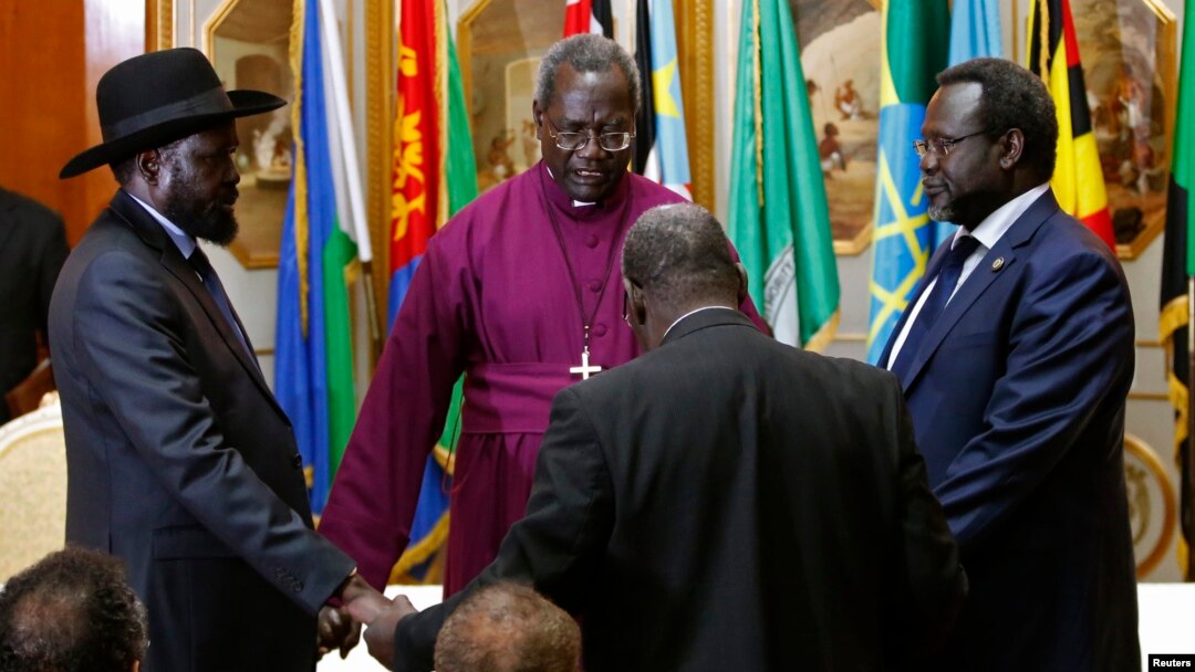 FILE - South Sudan's rebel leader Riek Machar (R) and South Sudan's President Salva Kiir (L) hold a priest's hands before signing an earlier peace agreement in Addis Ababa, Ethiopia, May 9, 2014.