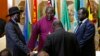 FILE - South Sudan's rebel leader Riek Machar (R) and South Sudan's President Salva Kiir (L) hold a priest's hands before signing an earlier peace agreement in Addis Ababa May 9, 2014.