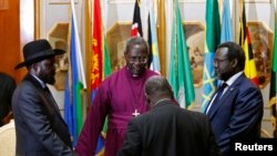 FILE - South Sudan's rebel leader Riek Machar, right, and South Sudan's President Salva Kiir hold a priest's hands before signing an earlier peace agreement in Addis Ababa, May 9, 2014.