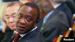 FILE - Kenya's President Uhuru Kenyatta turns to speak to a member of his delegation at the Somalia conference in London, May 7, 2013. 