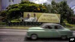 A man drives a vintage American car next to a display — which reads "Welcome to Cuba Pope Francis" in Spanish — at Revolution Square in Havana, Cuba, Sept. 15, 2015.