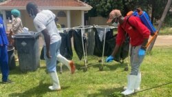 A health official sprays a colleague with a disinfectant Feb. 18, 2021, at Wilkins Hospital in Harare, where Zimbabwe launched its COVID-19 vaccination program. (Columbus Mavhunga/VOA)