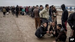 FILE - Iraqis displaced from Mosul receive aid distributions at near Qayara, Iraq, Dec. 28, 2016.