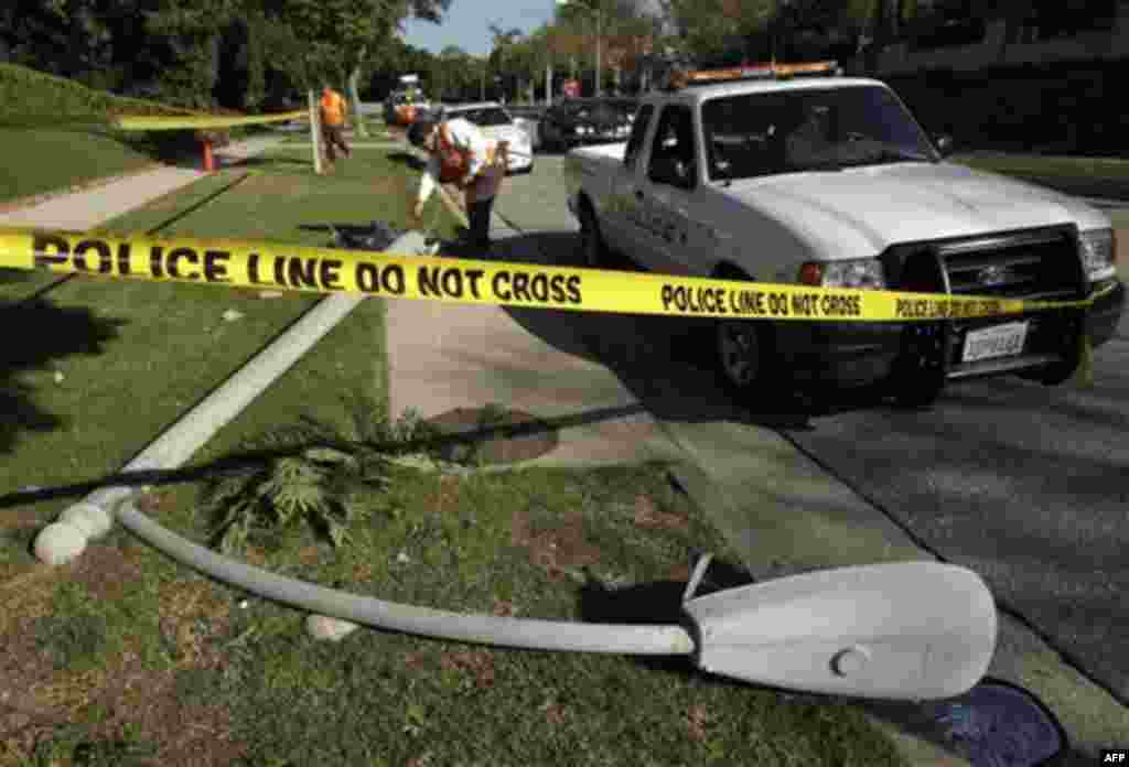 A utility worker examines the site of a crash where a woman, Hollywood publicist Ronni Chasen, 64, was found inside her vehicle shot several times in the chest and killed, afterward crashing into this light pole early Tuesday, Nov 16, 2010 in Beverly Hill