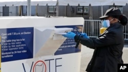 Marcia McCoy drops her ballot into a box outside the Cuyahoga County Board of Elections, April 28, 2020, in Cleveland, Ohio.