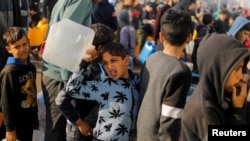 Palestinska djeca čekaju u redovima vodu za piće u Rafi