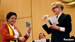 UNHCR goodwill ambassador and actress Cate Blanchett (R) and formerly stateless refugee Maha Mamo (L) show passports during the UNHCR's Executive Committee meeting in Geneva, Switzerland, Oct. 7, 2019.