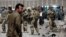 FILE - US forces and Afghan security inspect the site after a suicide bombing attack near Kabul's international airport in Kabul, Afghanistan, May 17, 2015. 