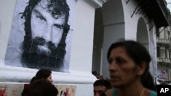 A woman walks past an image of Santiago Maldonado during a protest demanding justice for his death, in Buenos Aires, Argentina, Nov. 1, 2017. The body of Maldonado was found near the site of a protest on Aug. 1, the day he was last seen alive.