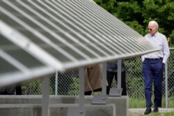 FILE - Then-Democratic presidential candidate Joe Biden looks at an array of solar panels during a tour at the Plymouth Area Renewable Energy Initiative in Plymouth, N.H., June 4, 2019.