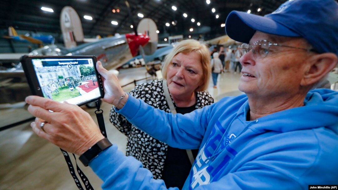 In this Friday, April 26, 2019 photo, Deane Sager, of Louisville, right, and his wife Cathy use a Histopad tablet to view scenes from operations on the western front of World War II at the The National Museum of the U.S. Air Force, in Dayton, Ohio. (AP Photo/John Minchillo)