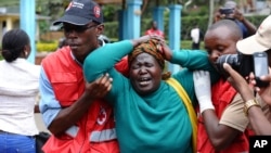 Le personnel Croix-Rouge kényane aide une femme en pleurs après qu'elle a vu le corps d'un parent tué dans l'attaque de jeudi dans une université, au Chiromo de maison funéraire, Nairobi, Kenya, jeudi 3 Avril 2015.