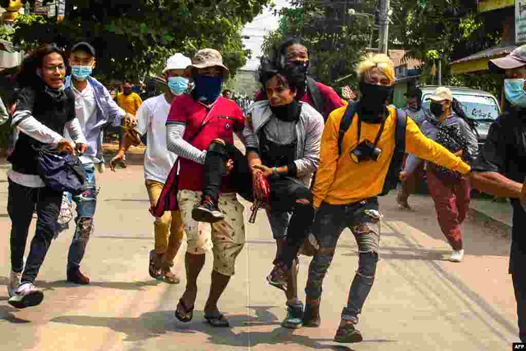 Protesters carry an injured comrade during a demonstration against the military coup in Yangon&#39;s Thaketa township, Myanmar.