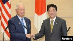 PM Jepang Shinzo Abe (kanan) berjabat tangan dengan PM Malaysia Najib Razak dalam rangkaian acara KTT Jepang-ASEAN di Tokyo 12/12/ 2013.