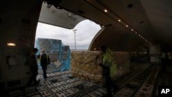 FILE - Air France cargo workers load equipment and pharmaceutical containers in a cargo plane at Roissy airport, outside Paris, Nov. 25, 2020, as the company is preparing for the transport of COVID-19 vaccines.