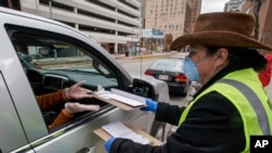 Jill Mickelson helps a drive up voter outside the Frank P. Zeidler Municipal Building Monday March 30, 2020, in Milwaukee. 