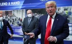 U.S. President Donald Trump holds a protective face mask with a presidential seal on it that he said he had been wearing earlier in his tour, out of the media's sights, at the Ford Rawsonville Components Plant in Ypsilanti, Michigan, May 21, 2020.