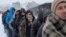 Migrants wait in line to receive plates of free food during a snowfall outside a derelict customs warehouse in Belgrade, Serbia, Jan. 18, 2017. 