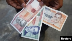 FILE - A man shows a new Cuban pesos outside a bank in Havana, Feb. 2, 2015. 