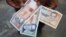 FILE - A man shows a new Cuban pesos outside a bank in Havana, Feb. 2, 2015.  
