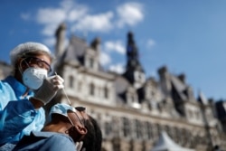 A health worker prepares to collect a nasal swab from a person at a COVID-19 testing site in front of the city-hall in Paris, France, Sept. 2, 2020.