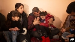 In this Feb. 12, 2020 photo, Malak Saad Dakhel, an 11 year-old Yazidi, is overwhelmed by journalists and well-wishers as her family tries to comfort her after her escape from Syria, in Sharia, Iraq. She was captured by Islamic State militants in 2014.