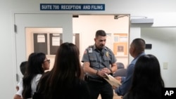 FILE - An officer listens to a question as he directs people to a courtroom in an immigration court in Miami, Florida, Jan. 10, 2024.