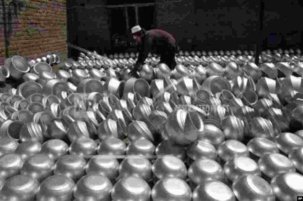 An Afghan laborer arranges pots at an aluminum factory, on Surkh Rod district of Jalalabad east of Kabul, Afghanistan.